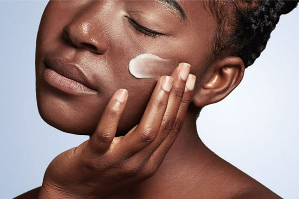 Ausschnitt einer jungen Frau mit unreiner Haut bei der Feuchtigkeitspflege fürs Gesicht